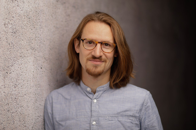 Portrait of a man with glasses and half-length hair, light blue shirt