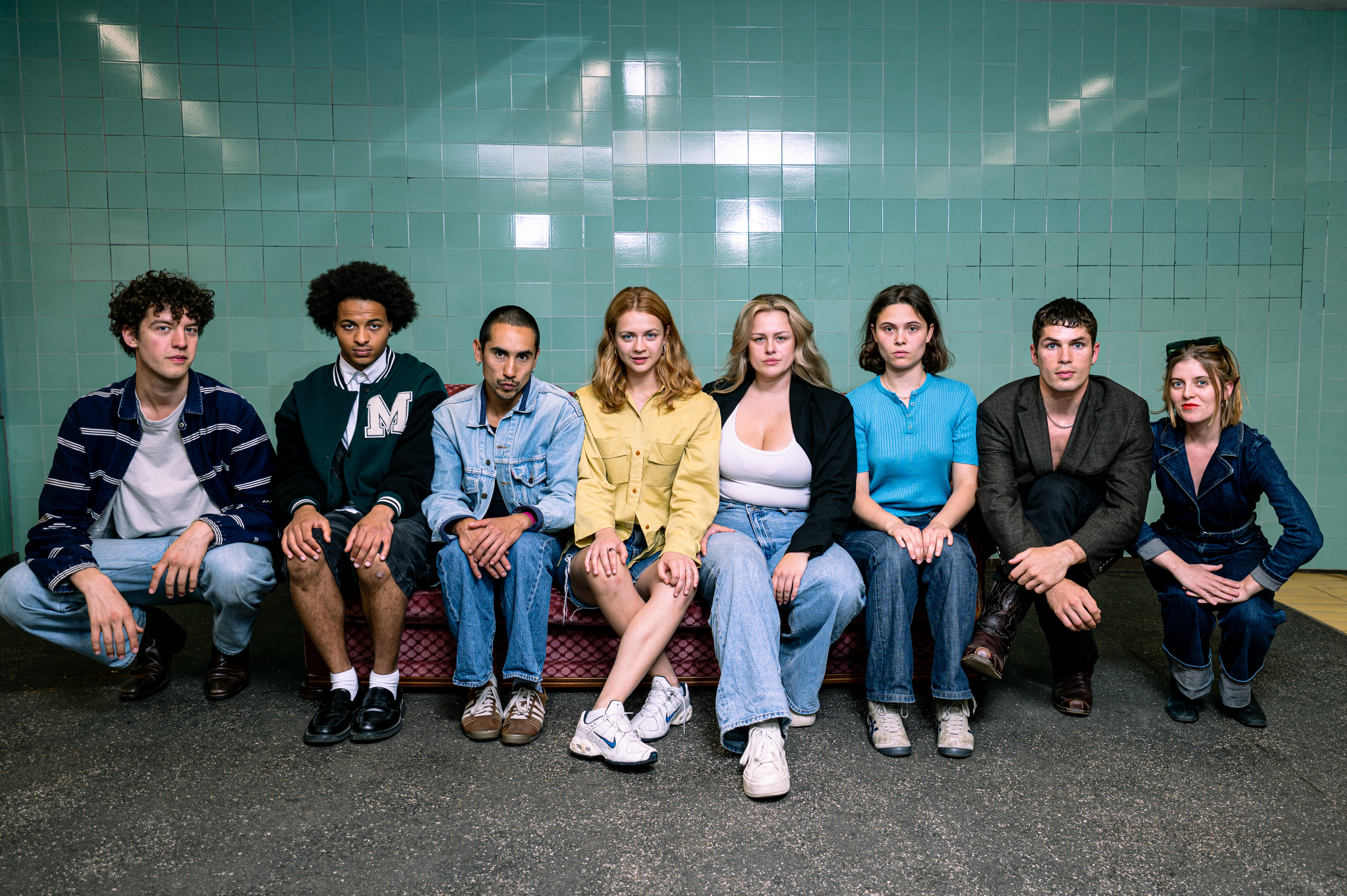 Eight people are sitting on a sofa.