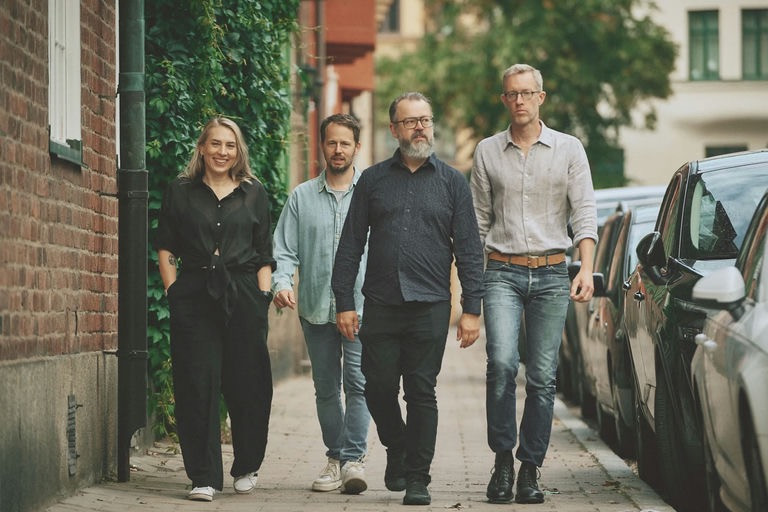 vier Personen laufen auf einem Gehweg der Kamera entgegen